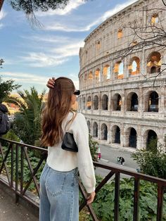 a woman standing in front of the colossion looking out at the street below