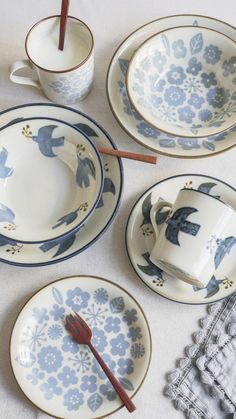 the table is set with blue and white plates, cups, and utensils