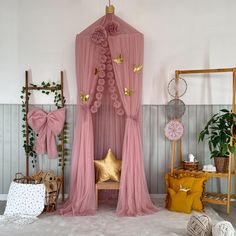 a pink canopy bed sitting next to a wooden chair and potted plant in a living room