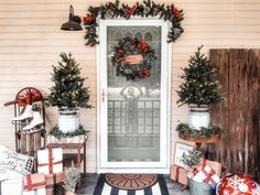 a front porch decorated for christmas with presents and wreaths