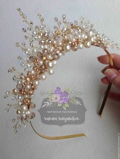 a hand holding a piece of gold and white beaded hair comb with pearls on it