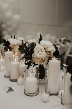 white flowers and candles are arranged on the table for a formal dinner or wedding reception