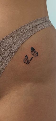 a woman's stomach with two butterflies tattoo on her left side ribcage