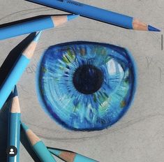 some pencils are laying on the ground next to an eye drawn in blue and green