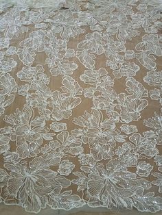 an image of a table cloth with white flowers and leaves on brown paper behind it