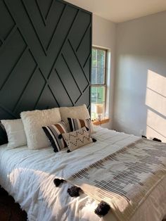 a bed with white sheets and pillows in a bedroom next to a large wall decoration