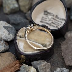 an open ring box sitting on some rocks