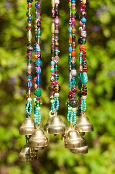 three bells hanging from a tree with beads