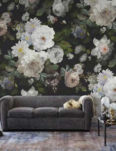 a living room with floral wallpaper and grey couch