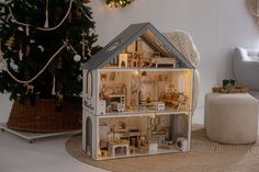 a doll house sitting on top of a rug next to a christmas tree