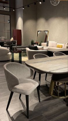 a table and chairs in a room with couches, tables and mirrors on the wall