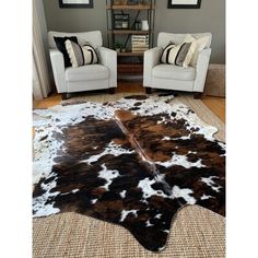 a living room with two chairs and a cowhide rug