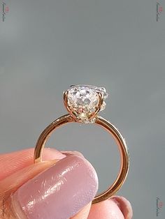 a close up of a person's hand holding a ring with a diamond on it