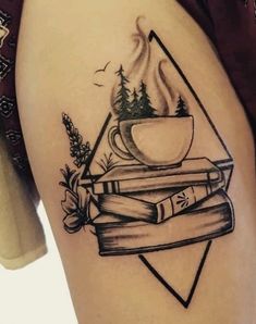 a woman's thigh with books and a cup on it