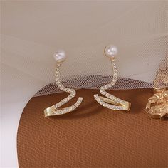 18k gold-plated earrings detailed with cubic zirconia stones and pearls in a unique wave design. 0.87" W x 1.38" L 18k gold-plated copper / cubic zirconia / pearl Stud Piercing, Ear Clips, Snake Earrings, Ear Cuffs, Crystal Stud Earrings, Crystal Drop Earrings, Trendy Jewelry, Fashion Accessories Jewelry, Pearl Studs