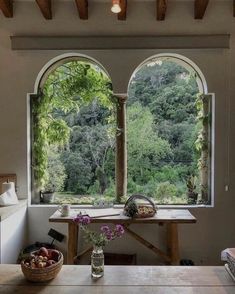 an open window in a living room with two vases filled with flowers and fruit on the table