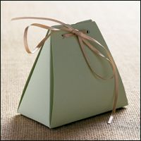 a small green box with a brown ribbon on it's side sitting on the floor