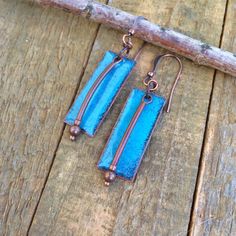 Artsy turquoise glass enameled copper earrings with antiqued copper accents.I create these unique, recycled copper earrings by cutting rectangle of pure copper then torch firing on layers of color glass powder. The effect is a rustic, weathered, turquoise blue glass finish that is unique to each pair made. I then add a dangle accent piece made of various shaped antiqued copper. As the backs cannot be enameled they are left as pure copper. These earrings are very light weight and are perfect for Artsy Earrings, Earthy Jewelry, Rustic Blue, Hammered Earrings, Copper Accents, Hand Painted Jewelry, Enamel Beads, Enameled Copper, Earrings Geometric