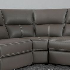 a grey leather couch sitting on top of a carpeted floor next to a wall