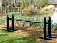 two black metal benches sitting in front of a pond