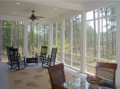 a screened porch with rocking chairs and table