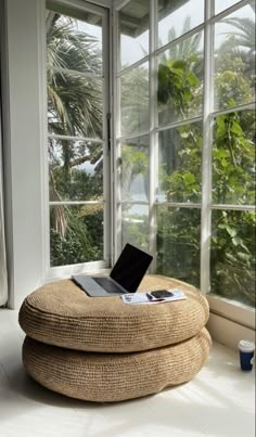 a laptop computer sitting on top of a round ottoman