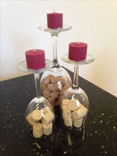 three wine glasses with candles and corks in them sitting on a black counter top