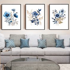 three blue flowers are hanging on the wall above a white couch in a living room