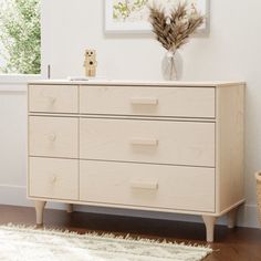 a white dresser sitting in a living room next to a window