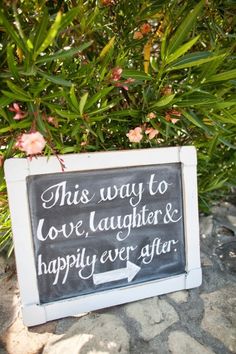 this way to love laughter happily ever after sign in front of some bushes with pink flowers