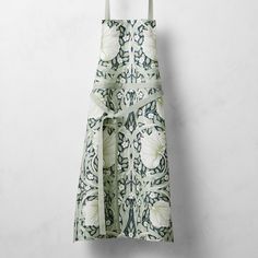 an apron hanging on a wall with a flower print pattern and bow tie at the waist