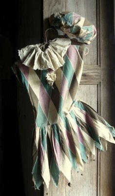 an old dress hanging on the wall in front of a wooden door with peeling paint