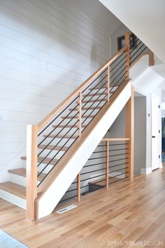 an empty living room with stairs and hard wood flooring on the wooden floor in front of white painted walls