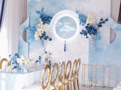 there is a blue and white wall with flowers on it, along with gold chairs