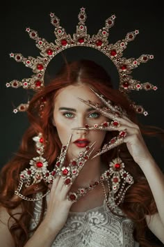 a woman with red hair wearing a tiara and holding her hands to her face