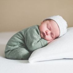 a newborn baby sleeping on top of a white pillow and wearing a knitted hat