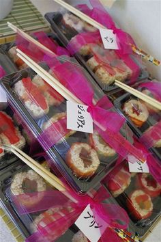 there are many sushi in plastic containers with chopsticks sticking out of them