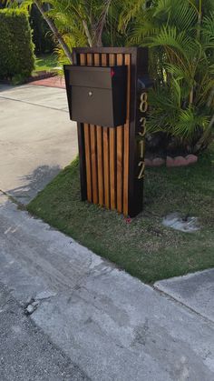 a mailbox sitting on the side of a road next to a tree and bushes