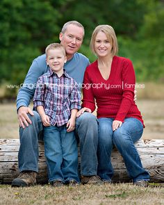 a man, woman and child sitting on a log