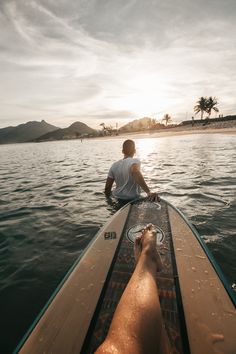 a man sitting on top of a surfboard in the ocean next to another person