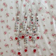 three pairs of dangling earrings with red and white beads on a floral fabric covered sheet