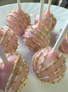 pink and white cake pops with gold sprinkles on a white platter