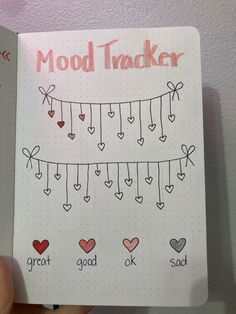 a hand holding a notebook with doodles and hearts on it that says mood trackerr