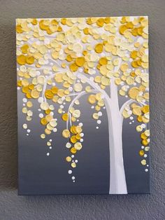 a painting with yellow and white leaves hanging on a wall next to a gray wall