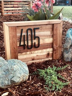 a wooden sign with the number forty5 on it in front of some rocks and flowers