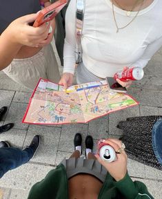 three people looking at a map on the ground while one person holds a cell phone