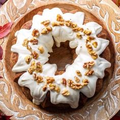 a bundt cake with white frosting and walnuts on top sitting on a plate