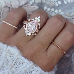 a woman's hand with two rings on it and an engagement ring in the middle