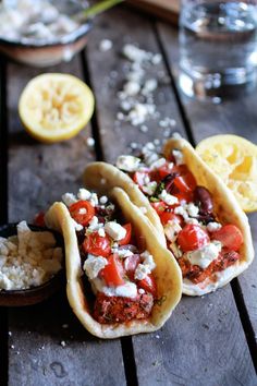 three tacos with meat, tomatoes and feta cheese