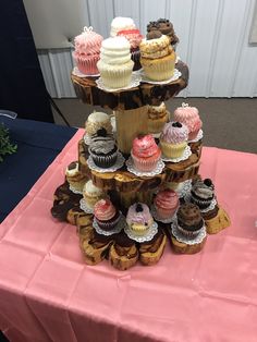 a table topped with lots of cupcakes on top of each other next to a pink table cloth